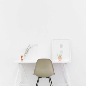 Minimalist office space featuring a white desk, chair, and framed art.