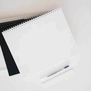 Overhead view of spiral notebooks, a pen, and a ruler on a desk.